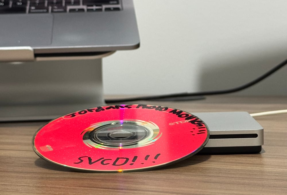 A disc with the text 'Jordans Photo Movies!!!' 'SVCD!!!' written on it, sitting on top of a USB DVD drive